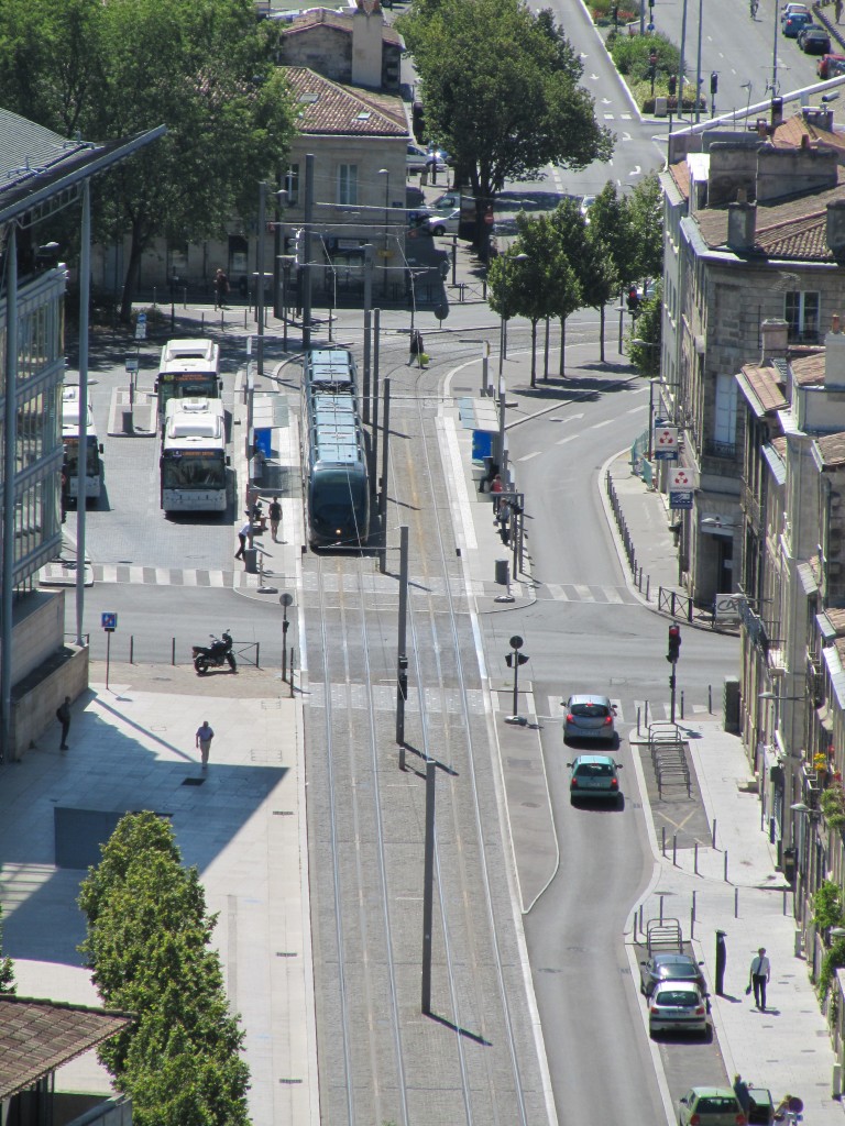 A tram transitions between overhead and ground-level power as it enters the central city